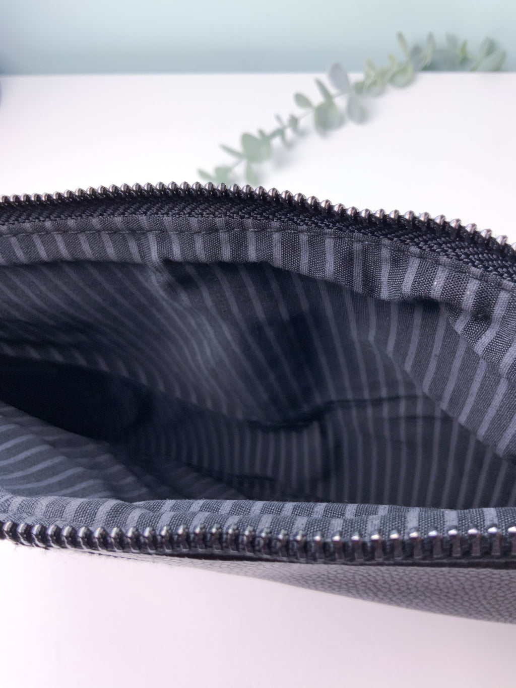Close-up of a striped fabric pouch with a zipper on a light background
